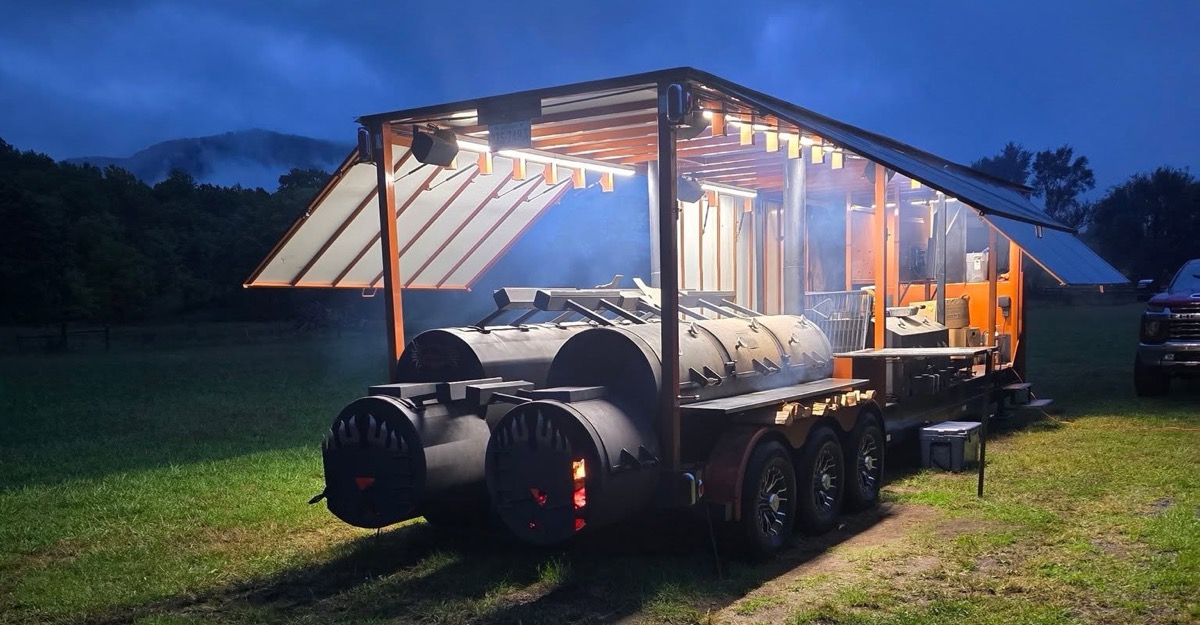 The rig at dusk with its fireboxes glowing and smoke drifting under the lit canopy